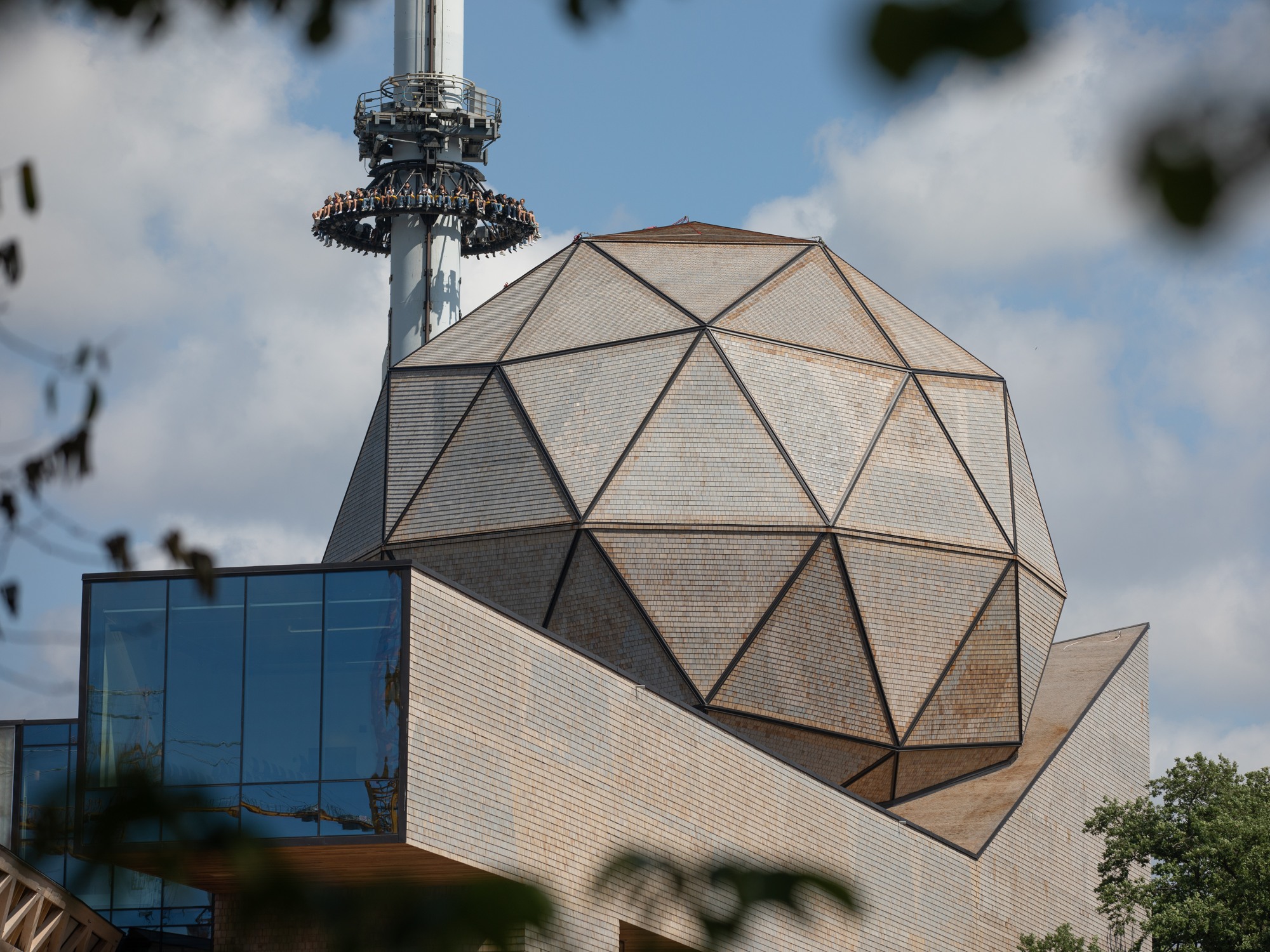 Visualiseringsdomen Wisdomes utsida, en glob täckt med triangulära paneler, bakom ser man Lisebergsattraktionen fritt fall 