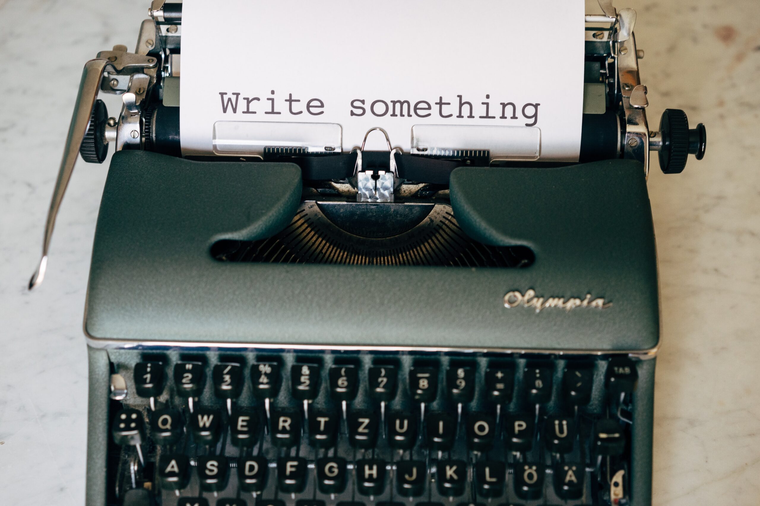 En gammaldags skrivmaskin, på pappret som kommer ut ur maskinen står det Write something