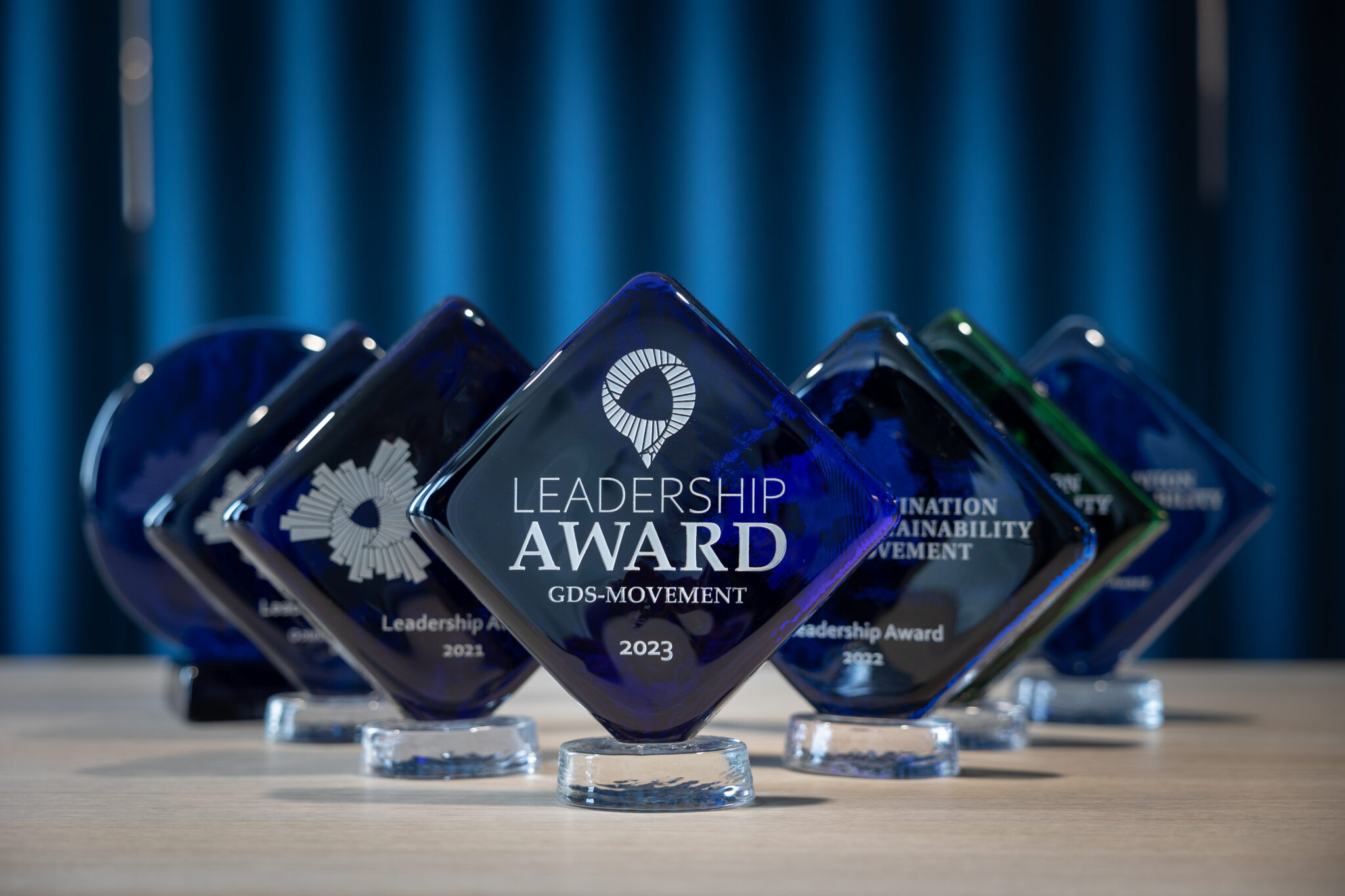 Leadership award trophies lined up in front of a blue background, with the most recent one from 2023 at the forefront.