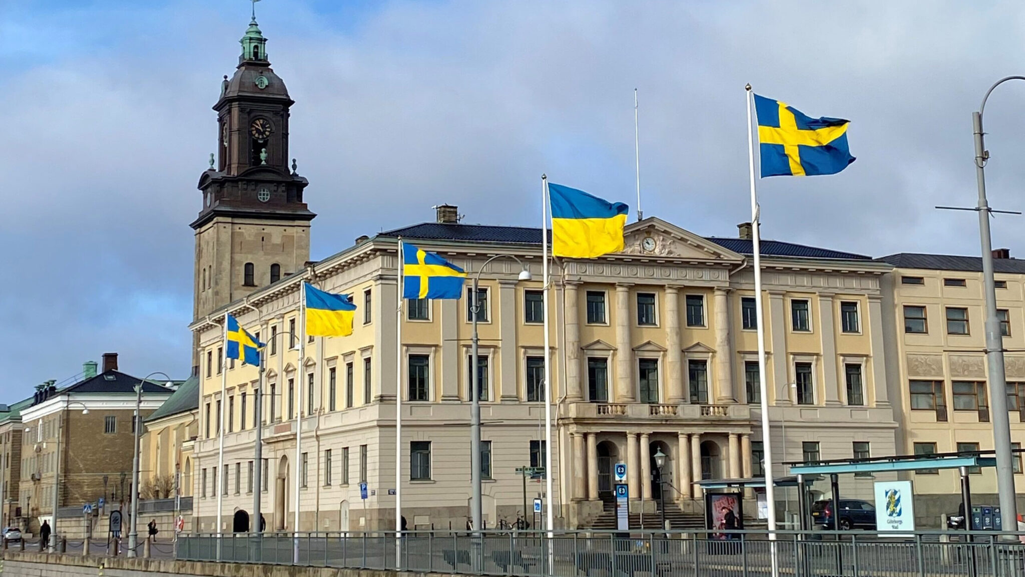 Fem flaggstänger framför Gustaf Adolfs torg i Göteborg, varannan flagga är svensk och varannan är ukrainsk